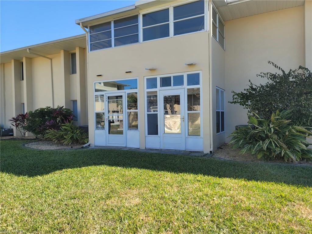View of exterior entry featuring stucco siding and a lawn