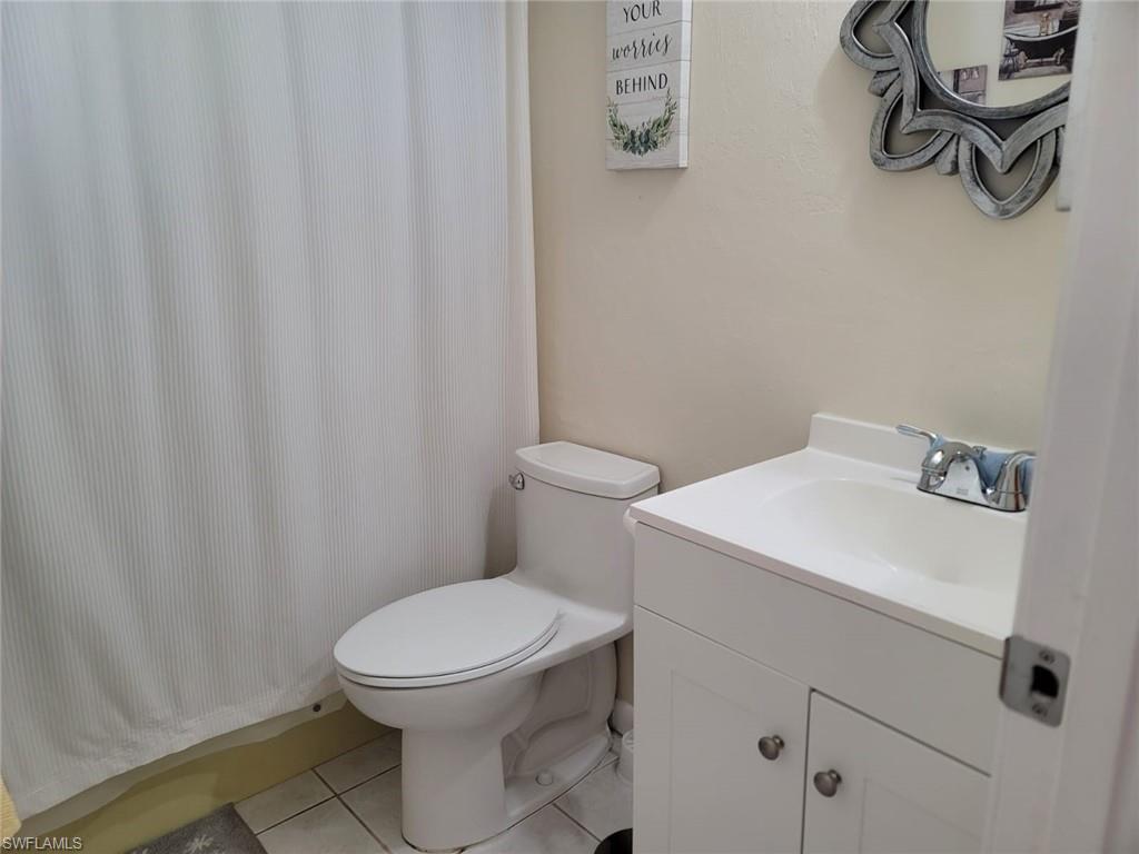 Full bathroom with vanity, a shower with curtain, and light tile patterned floors