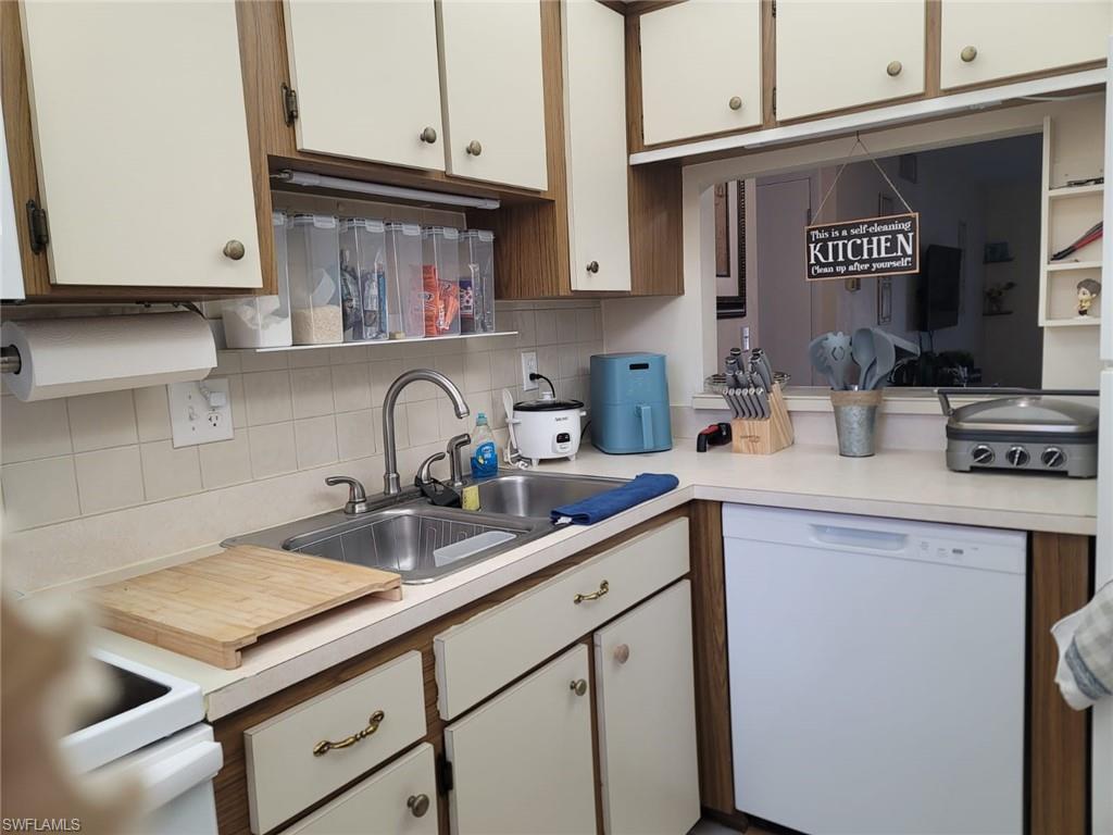 Kitchen featuring dishwasher, light countertops, decorative backsplash, and dual tone cabinetry
