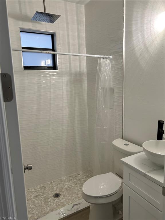 Bathroom with curtained shower, vanity, and toilet
