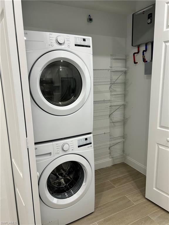 Washroom featuring stacked washing maching and dryer and light hardwood / wood-style flooring