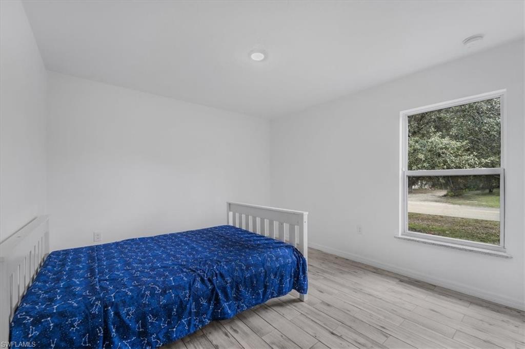 Bedroom with wood finished floors and radiator heating unit