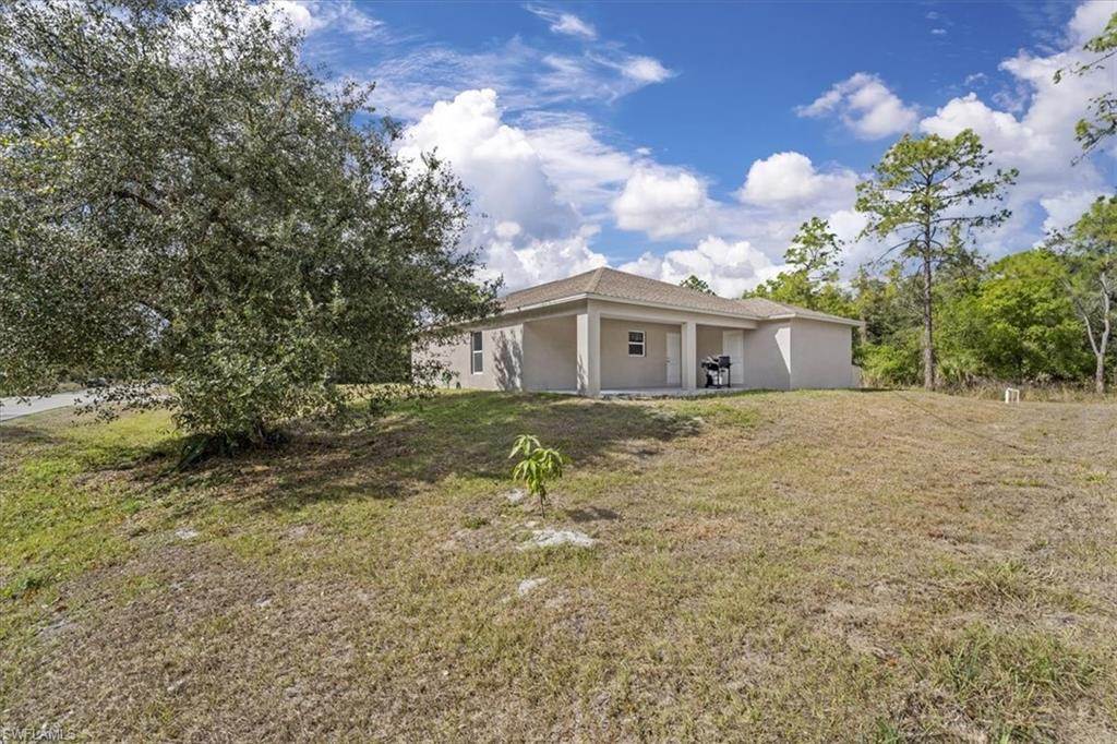 Back of house with stucco siding, a patio area, and a lawn