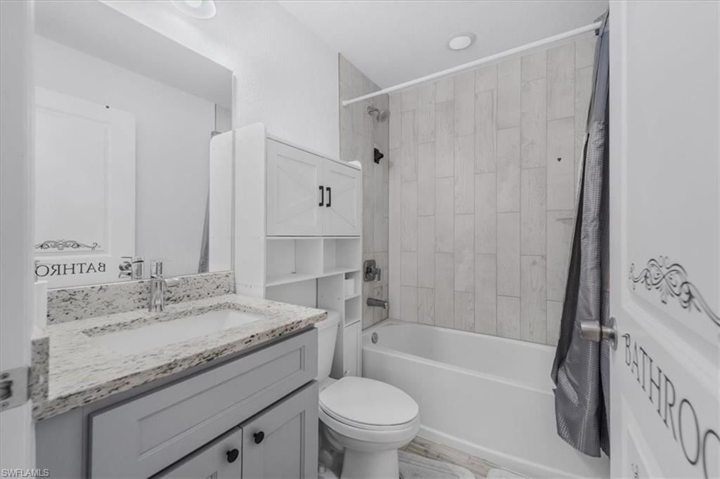 Bathroom with shower / bathtub combination with curtain and vanity