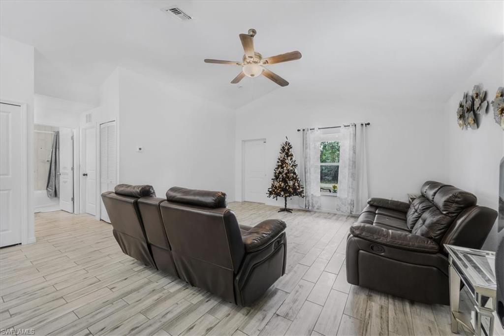 Living area featuring wood tiled floors, ceiling fan, and lofted ceiling