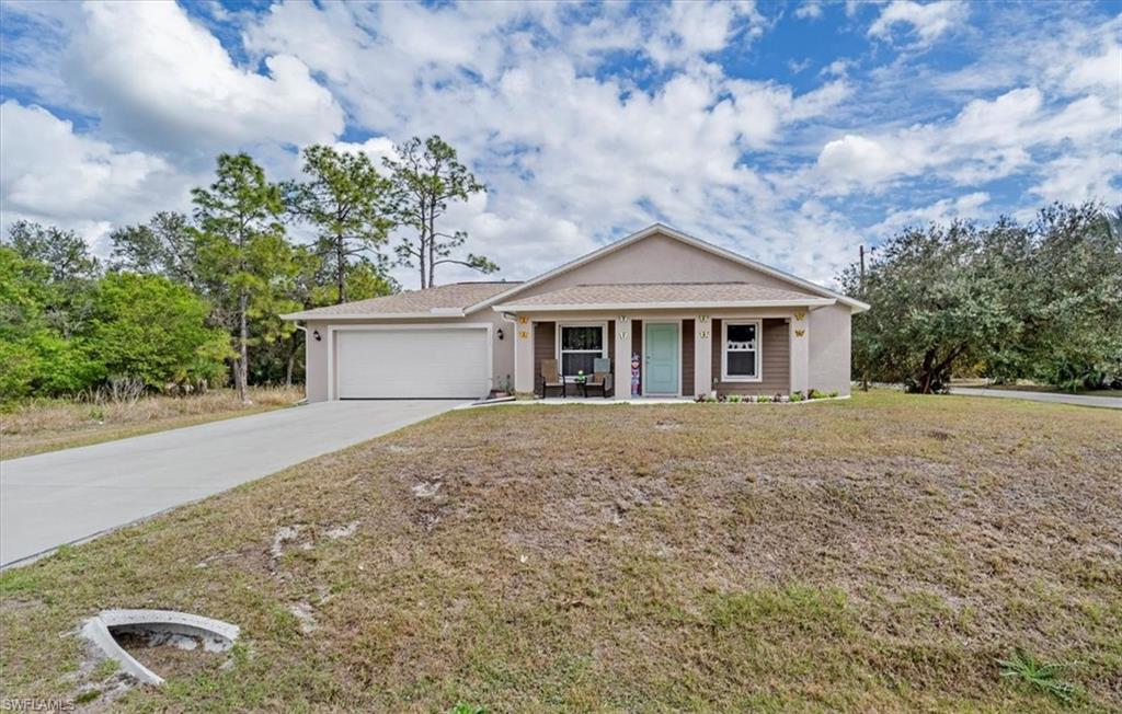 Ranch-style house featuring driveway, covered porch, an attached garage, and stucco siding