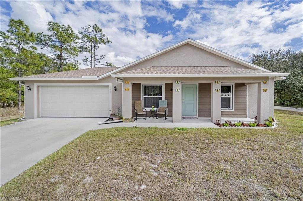 View of front of property with covered porch, roof with shingles, a front lawn, and driveway
