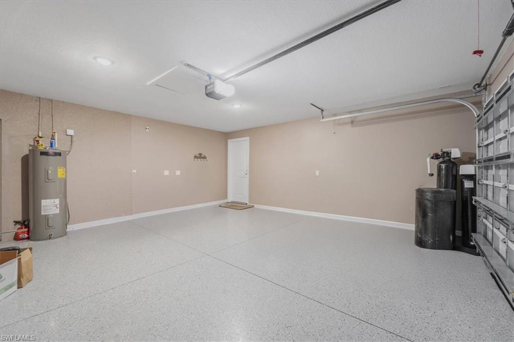 Garage featuring electric water heater and a garage door opener