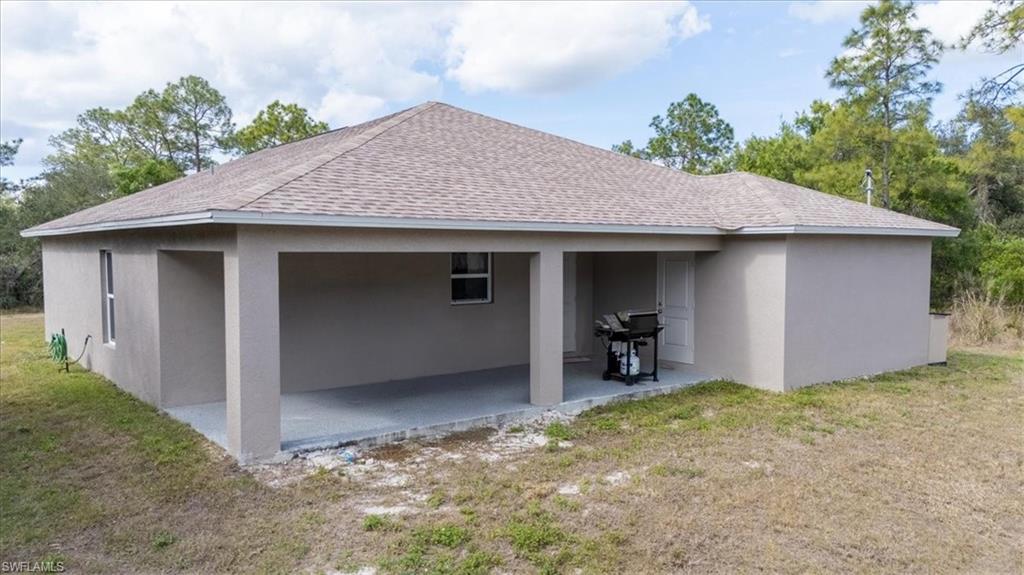 View of side of home featuring roof with shingles, stucco siding, and a yard