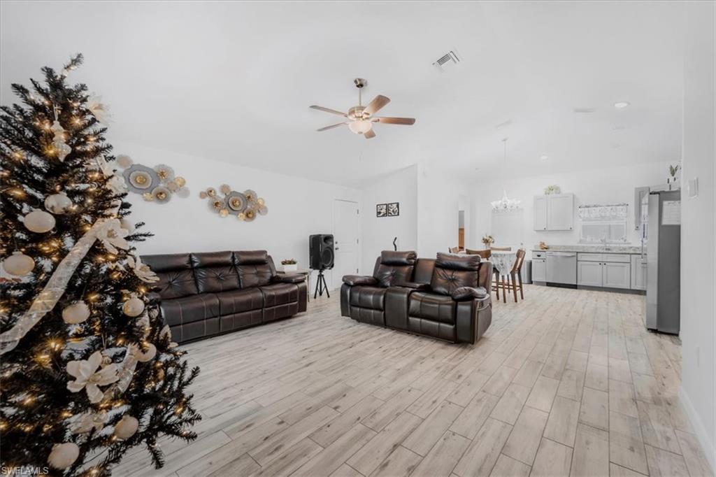 Living area featuring wood tiled floors, hanging lights, and ceiling fan
