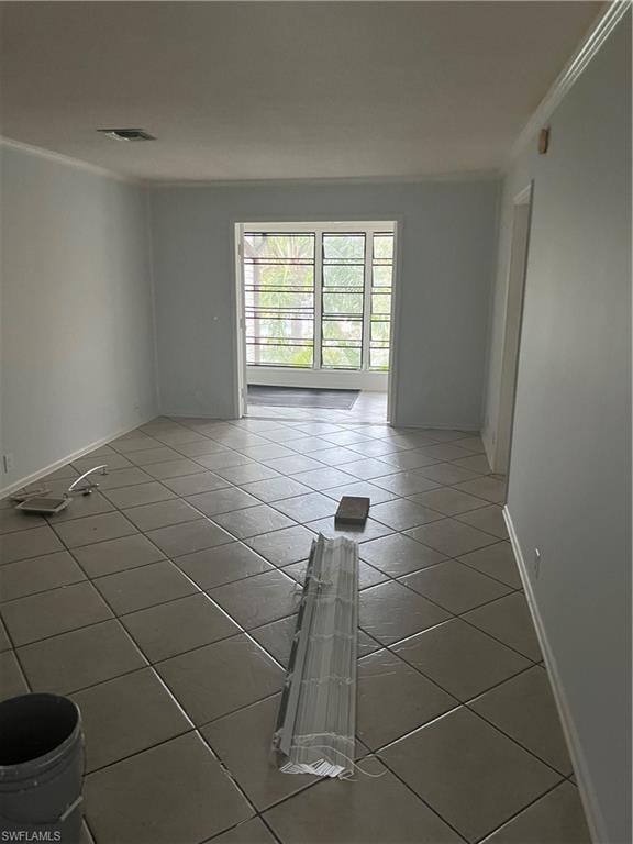 Tiled empty room featuring ornamental molding