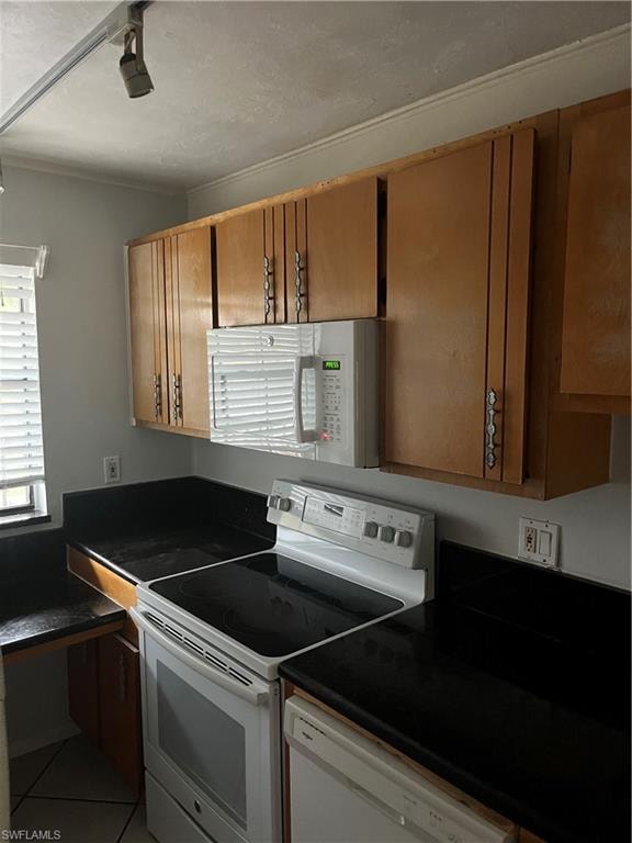 Kitchen with range, dark countertops, white microwave, and dishwasher