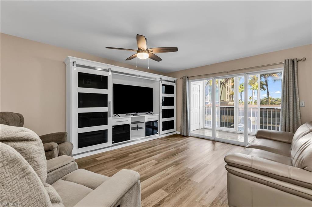 Living room featuring light wood-style floors, a ceiling fan, and a barn door