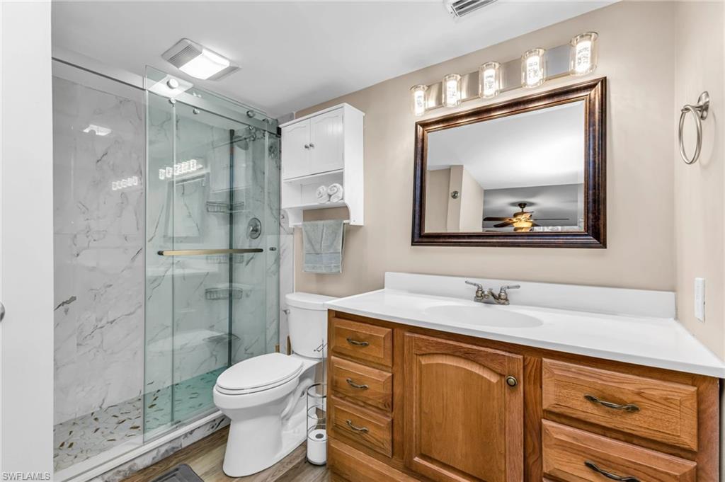 Full bath with vanity, a marble finish shower, and wood finished floors
