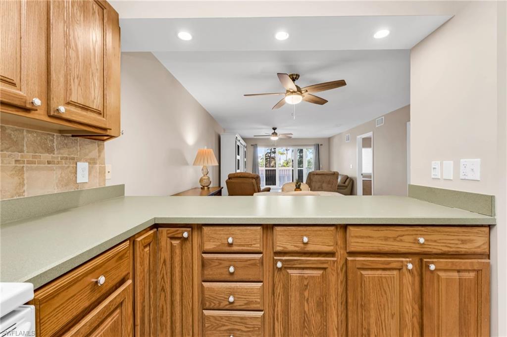 Kitchen featuring open floor plan, wood finish cabinetry, recessed lighting, backsplash, and ceiling fan
