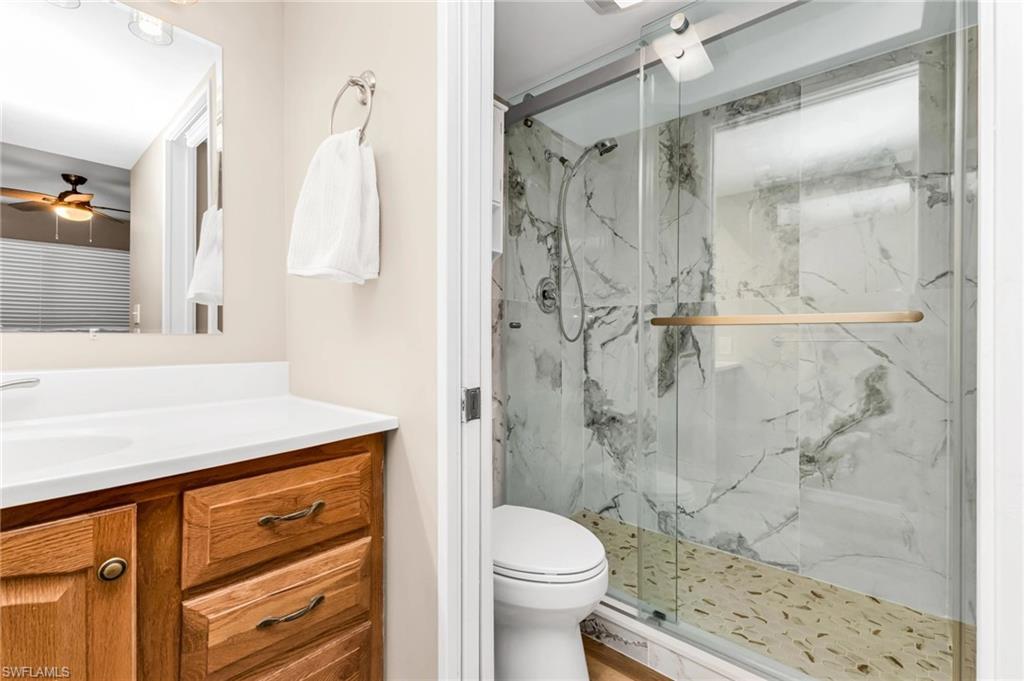 Full bath featuring vanity, ceiling fan, and a marble finish shower