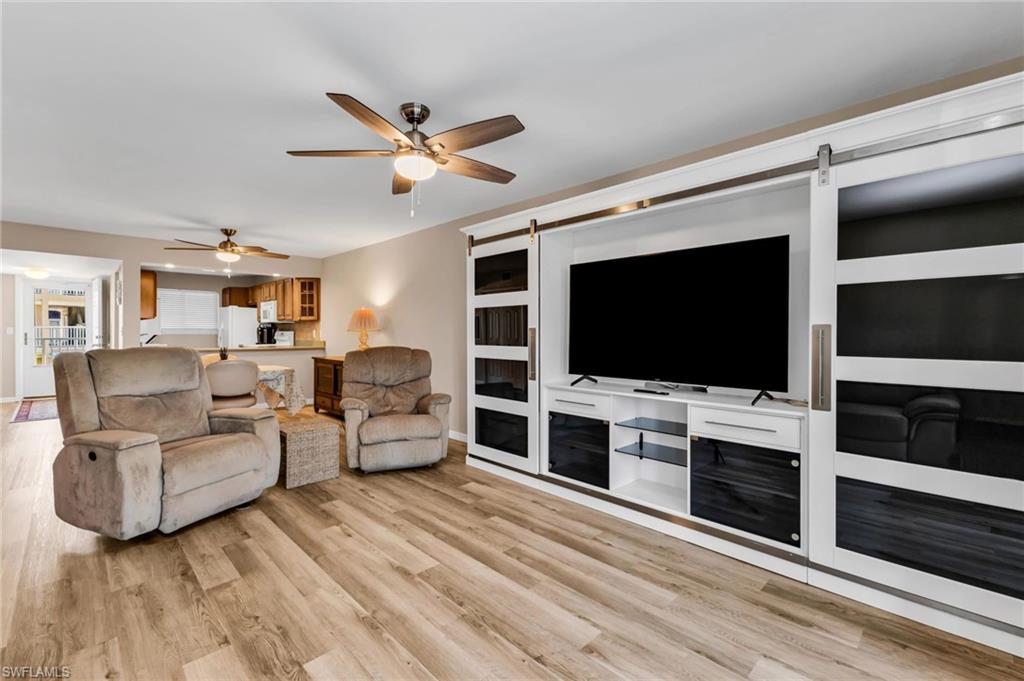 Living room with a barn door, light wood-style flooring, and ceiling fan