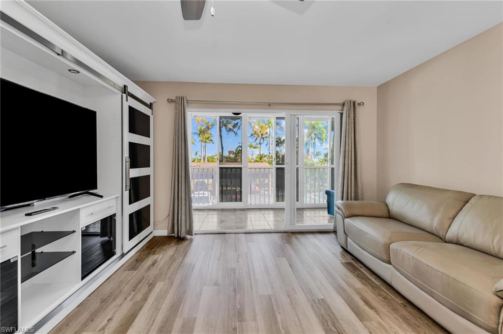 Living area with a barn door, ceiling fan, and light wood-type flooring