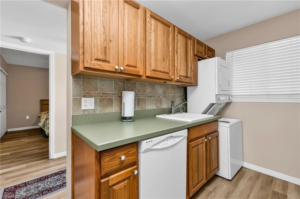Kitchen featuring dishwasher, wood finish cabinets, light wood finished floors, decorative backsplash, and light countertops