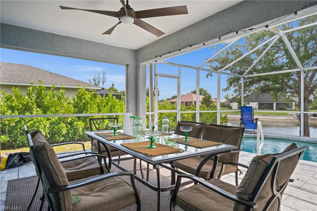 Sunroom featuring outdoor dining space, a ceiling fan, a water view, and a patio