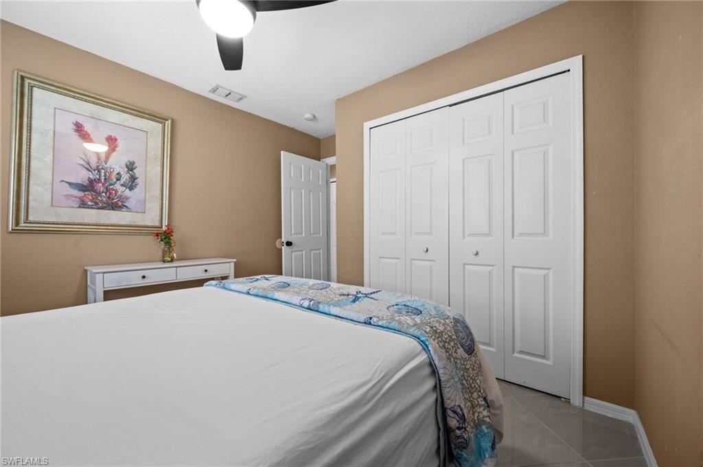 Tiled bedroom with a ceiling fan and a closet