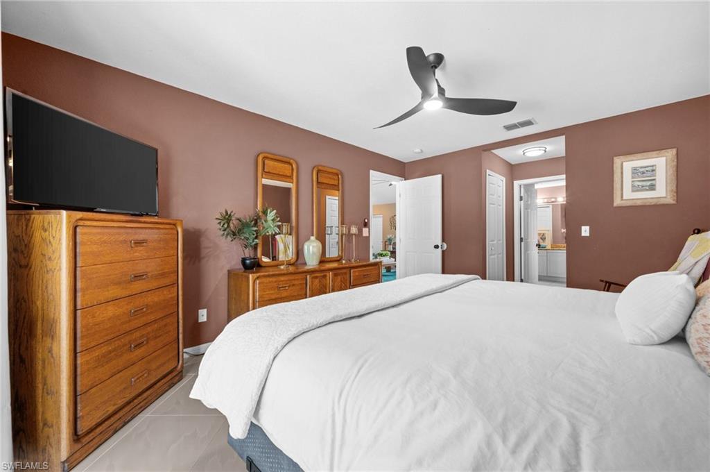 Bedroom with a ceiling fan, ensuite bathroom, and tile patterned floors