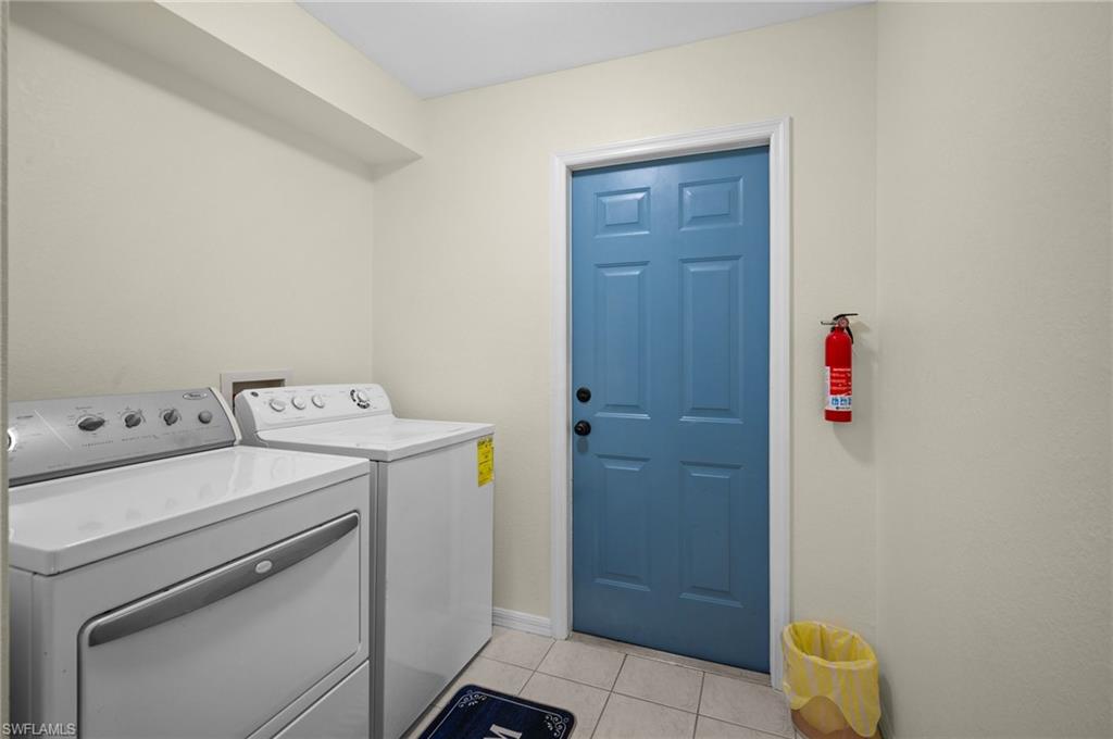 Laundry area featuring light tile patterned flooring and independent washer and dryer