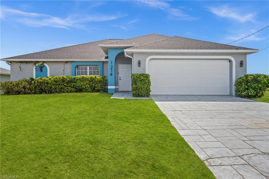 Ranch-style home with stucco siding, a front yard, driveway, an attached garage, and roof with shingles