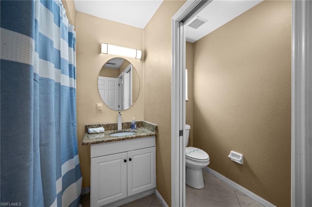 Bathroom featuring vanity, a shower with curtain, light tile patterned flooring, and a textured wall
