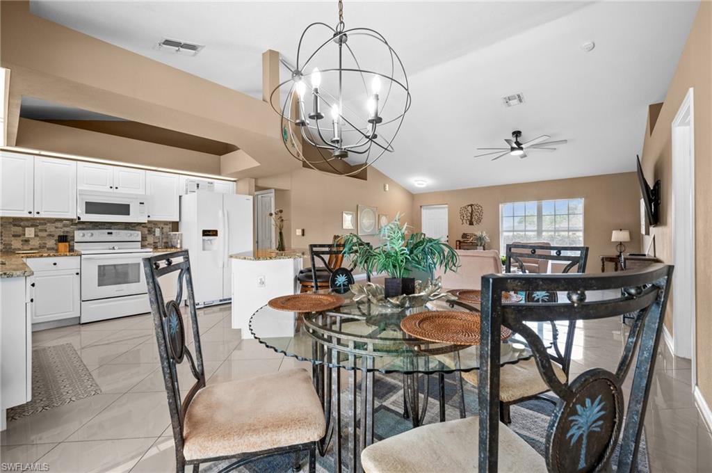 Dining area with suspended lighting, a ceiling fan, lofted ceiling, and light tile patterned flooring