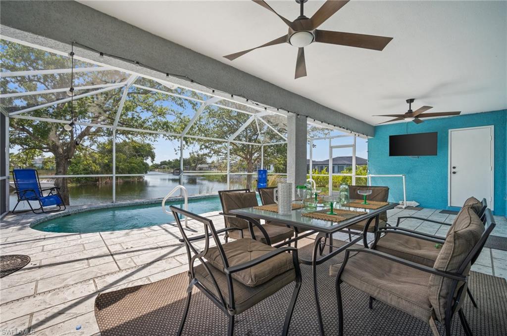 View of patio with a sunroom, glass enclosure, an outdoor pool, outdoor dining space, and a ceiling fan