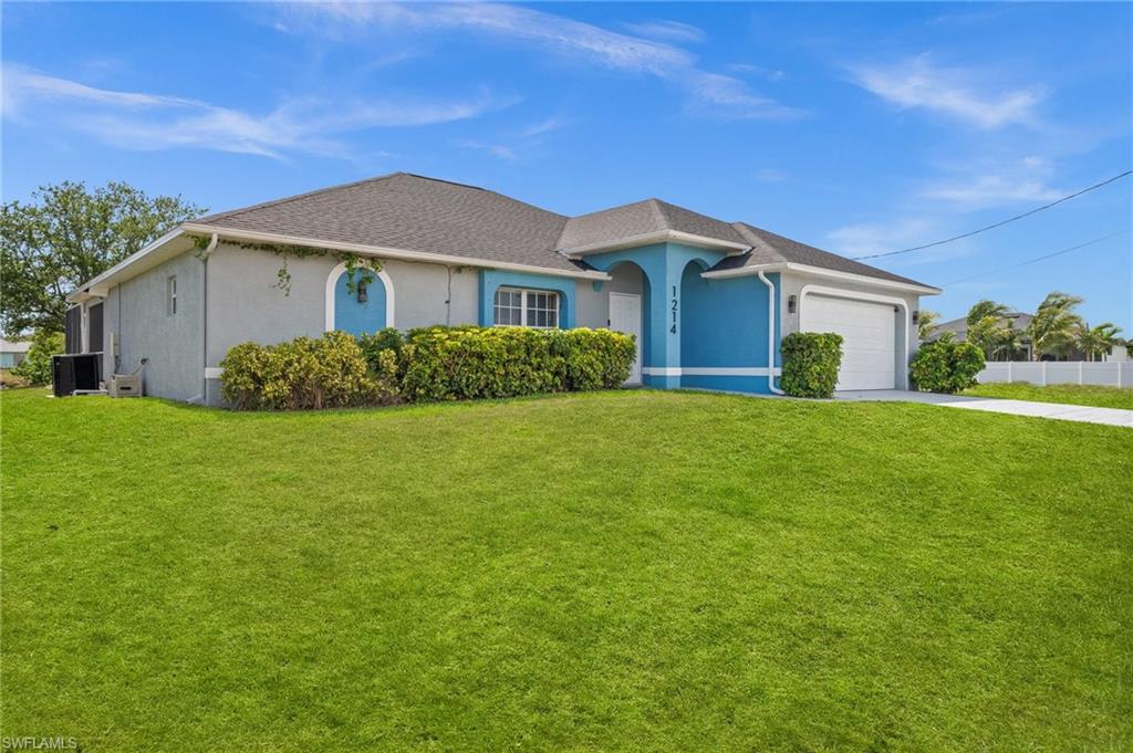Ranch-style home with stucco siding, a front yard, an attached garage, and concrete driveway