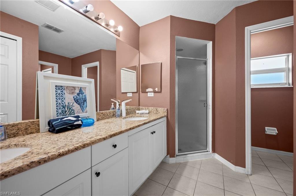 Bathroom with a stall shower, double vanity, and light tile patterned flooring