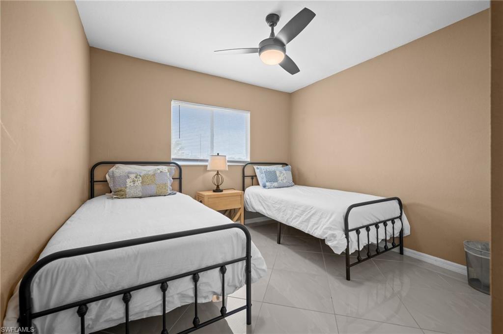 Tiled bedroom featuring baseboards and a ceiling fan