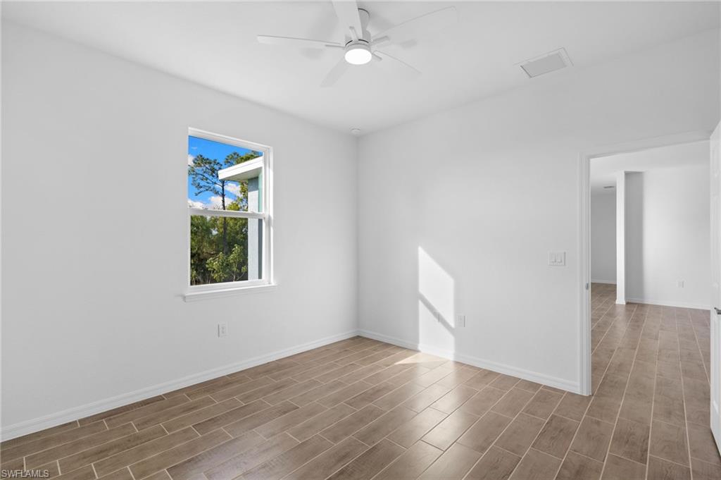 Empty room with wood tiled floors and a ceiling fan