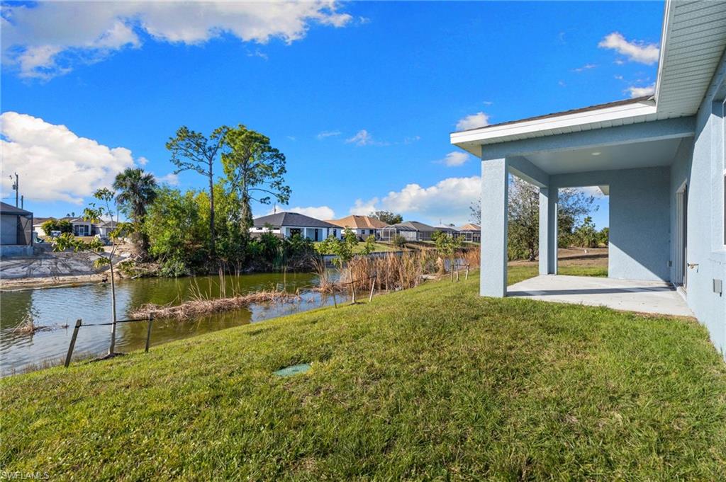 View of green lawn with a patio area, a residential view, and a water view