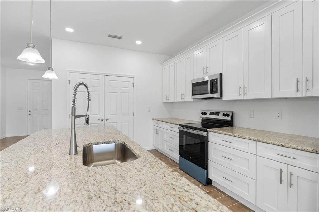 Kitchen with stainless steel appliances, white cabinetry, and wood tiled floors