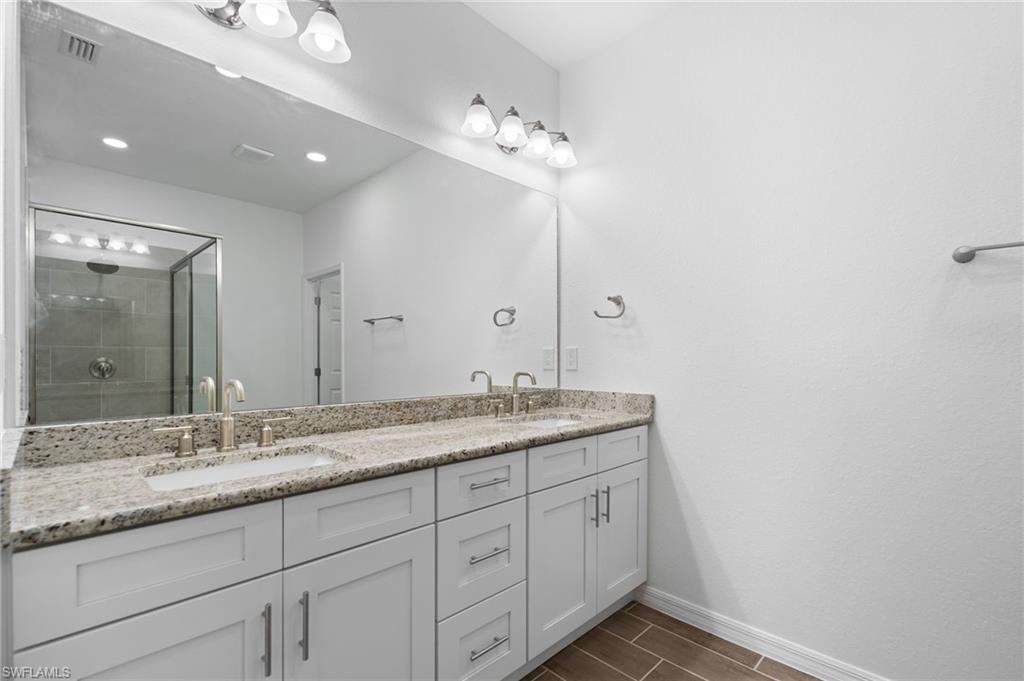Bathroom with double vanity, a shower stall, and wood tiled floors