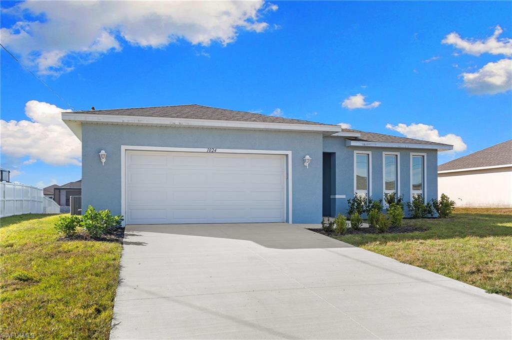 Ranch-style home featuring a front lawn, stucco siding, driveway, and an attached garage