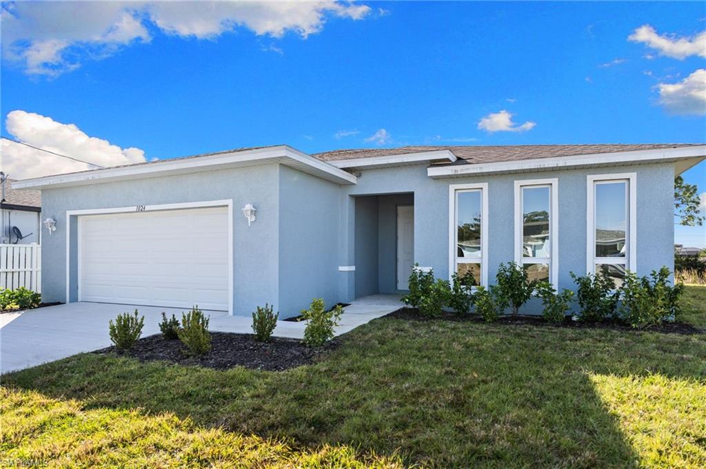 Ranch-style house with a front lawn, stucco siding, driveway, and an attached garage