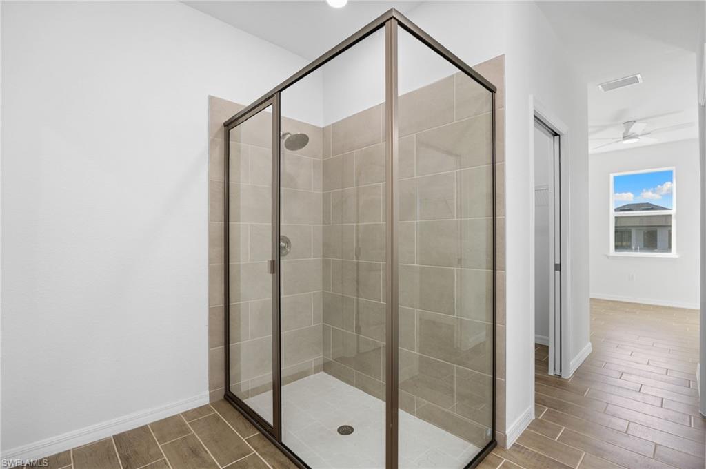Full bath featuring a shower stall, wood tiled floors, and ceiling fan