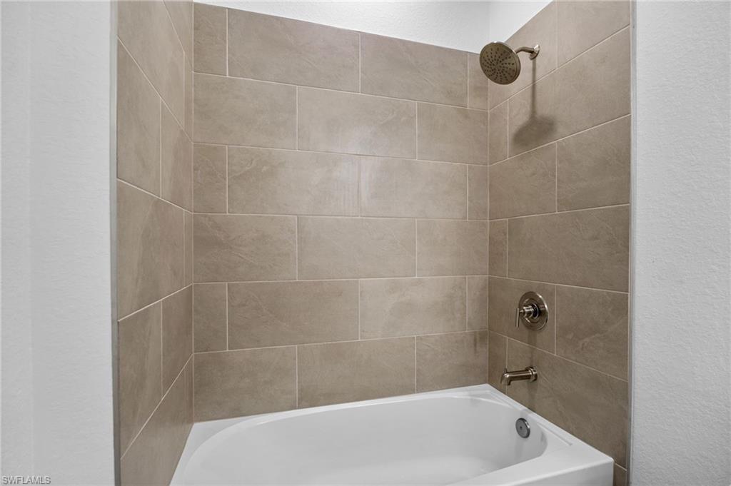 Full bathroom featuring bathing tub / shower combination and a textured wall