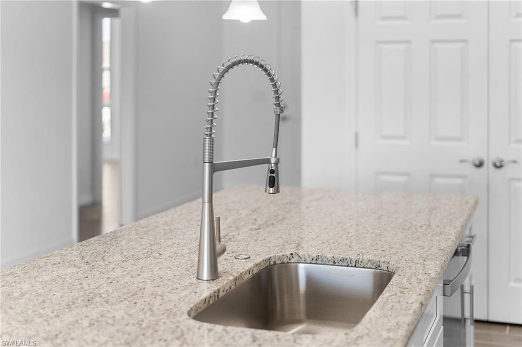 Kitchen view of light stone countertops, stainless steel dishwasher, and white cabinets