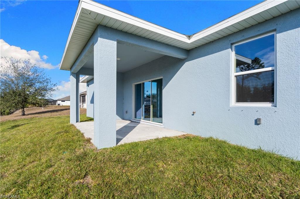 Back of house featuring stucco siding, a yard, and a patio area