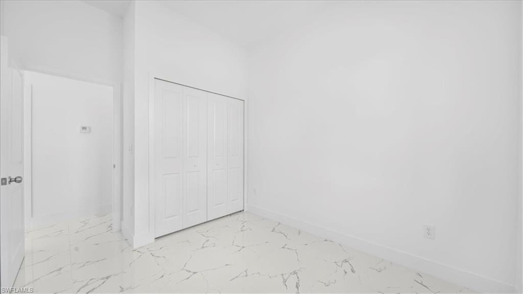 Unfurnished bedroom with a closet and light marble finish floors