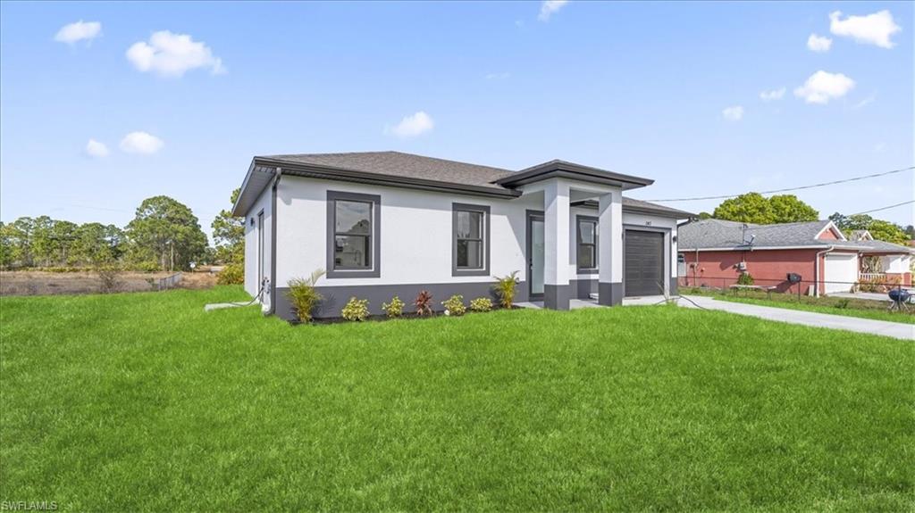 Prairie-style home featuring a front yard, stucco siding, and concrete driveway