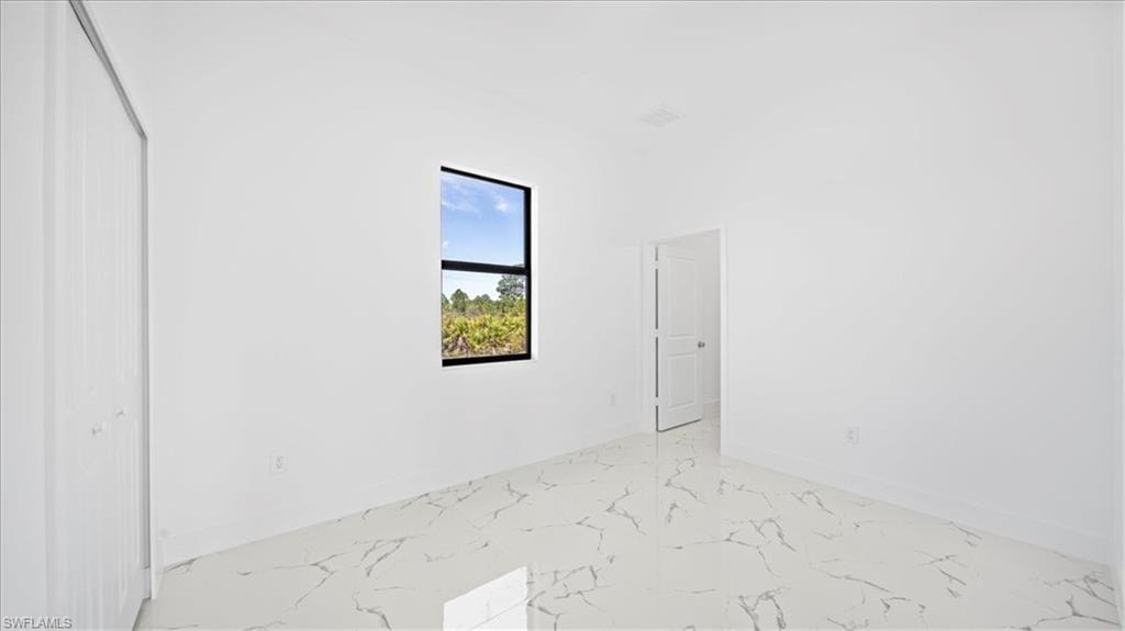 Unfurnished bedroom featuring light marble finish floors and a closet