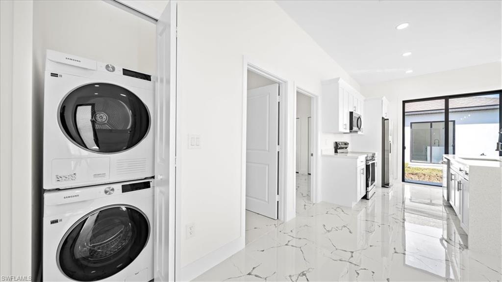 Laundry area featuring stacked washer / dryer, recessed lighting, and light marble finish floors