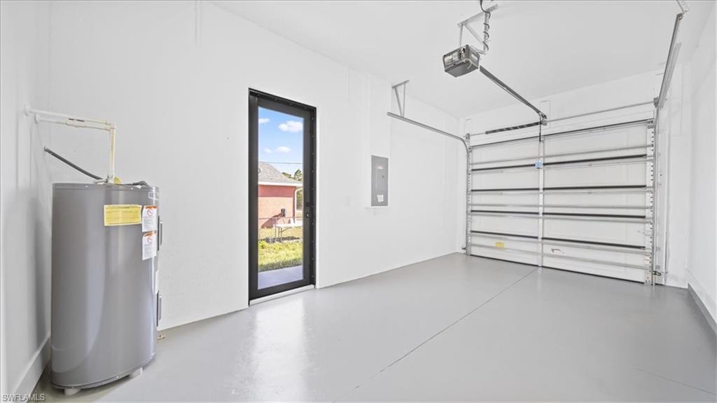 Garage with electric water heater, electric panel, and a garage door opener