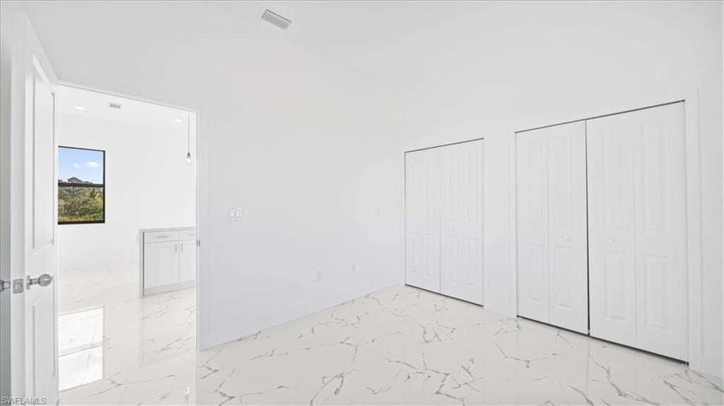 Unfurnished bedroom with light marble finish floors and two closets